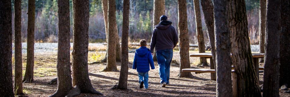 P&egrave;re et enfant en balade en for&ecirc;t dans le Queyras